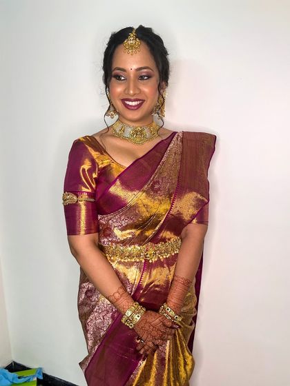 This full-length shot shows the bride's complete ensemble. The makeup is perfectly balanced with the rich colors and heavy gold of her Kanjivaram saree.