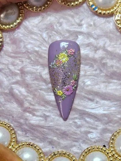A close-up of a student's hand-painted floral design with glitter accents. The detail and precision are a testament to their training.