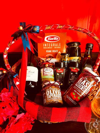 My 'Italian Romance' themed basket, perfect for a couple who loves a cozy night in. This gourmet hamper includes Barilla pasta, pasta sauce, olive tapenade, wine, and seasonings, all presented in a rustic basket with a red and blue theme.
