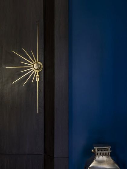 A detail from the son's bold blue bedroom, showcasing the custom sunburst-style hardware on the graphite veneer wardrobe. This is an example of how small details can make a powerful statement.