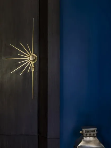 A detail from the son's bold blue bedroom, showcasing the custom sunburst-style hardware on the graphite veneer wardrobe. This is an example of how small details can make a powerful statement.