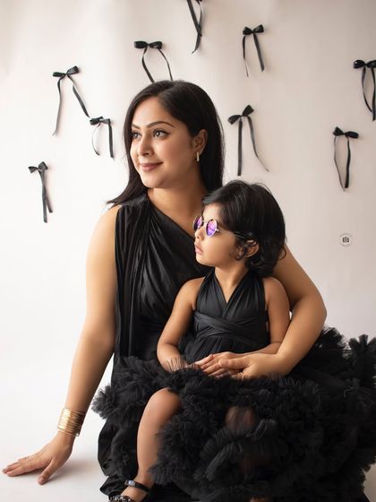 A mother and daughter duo in matching black outfits. This stylish portrait captures a quiet, shared moment between them.