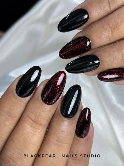 A sleek and mysterious black manicure with a touch of fire. The accent nails feature a subtle red sparkle within the black polish, giving the set a hint of sass and hidden glamour.
