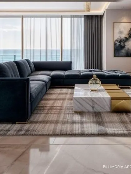 In this living room, a deep blue sectional sofa provides a rich pop of color against the neutral marble flooring and sheer curtains. The space is designed to feel open and connected to the outdoors, with a marble and gold coffee table anchoring the seating area.