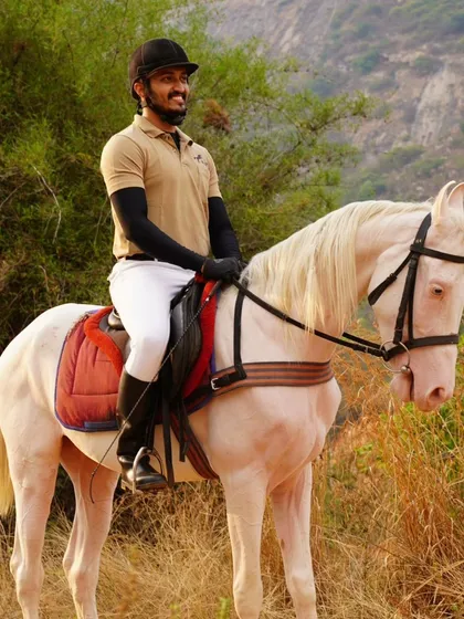 Dressed in full equestrian gear, this rider and his white horse pose against the lush greenery of our safari trail.