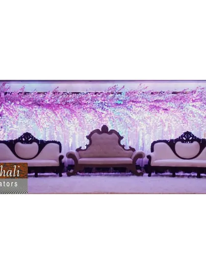 This minimalist yet beautiful stage features a three-piece sofa set against a wide backdrop of lit cherry blossom branches. The purple lighting creates a magical ambiance for any evening event.