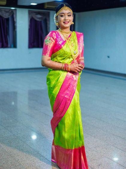 This bride is a vision in her bright lime green and pink Kanjivaram saree. The makeup is kept fresh and radiant to complement the vibrant colors of her outfit.