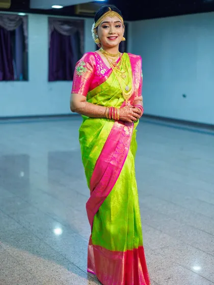 This bride is glowing in a bright parrot green and pink Kanjivaram saree. The drape is kept simple and elegant to let the vibrant colors shine.