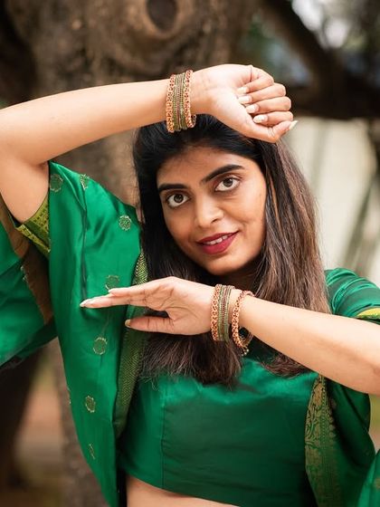 An artistic and expressive pose in a green saree. This outdoor shot showcases a blend of traditional dance posture and modern portraiture.