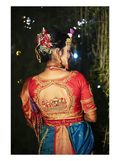 It's all in the details. This portrait highlights the stunning embroidery on the bride's blouse, featuring a traditional doli scene. We believe in capturing these personal touches that make your wedding attire unique.