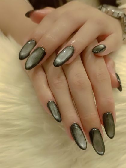 A dark and moody grey cat eye effect on long, oval-shaped nails.