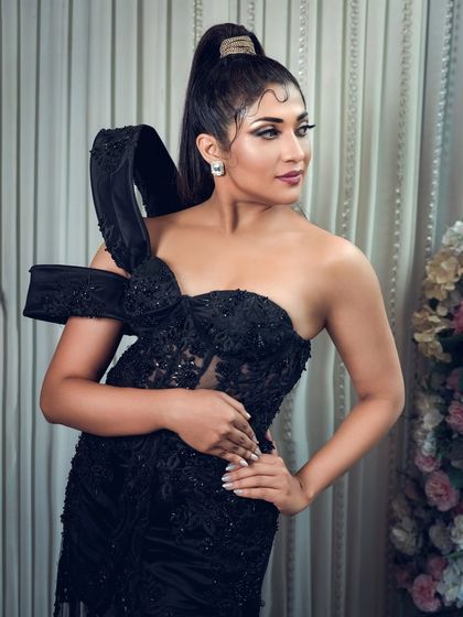 A full-length shot of actress Iti Acharya in an elegant black gown. This photo highlights the dress's unique design and is suitable for fashion features or red carpet-style portfolios.