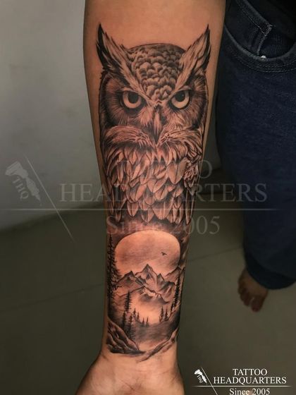A full forearm sleeve featuring a wise owl perched above a moonlit mountain landscape, showcasing our skill in large-scale realism.