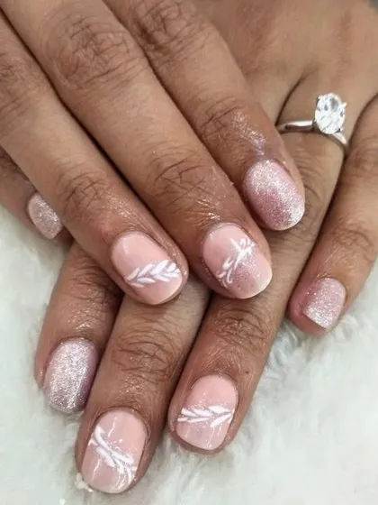 If you don't want extensions, you can get gel polish with art on your natural nails. This client chose a pink glitter base with delicate white leaf art.