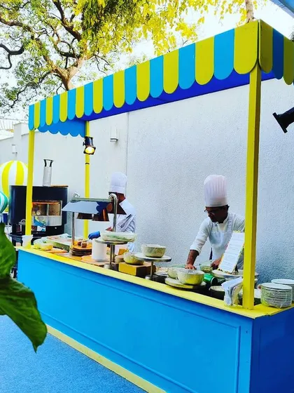 A quirky and colorful food station with a blue and yellow striped awning.