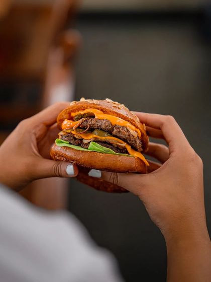 A close-up of our double-patty smashed burger, showcasing the perfectly melted cheese and juicy meat. We focus on the perfect meat-to-fat ratio for a melt-in-your-mouth texture.