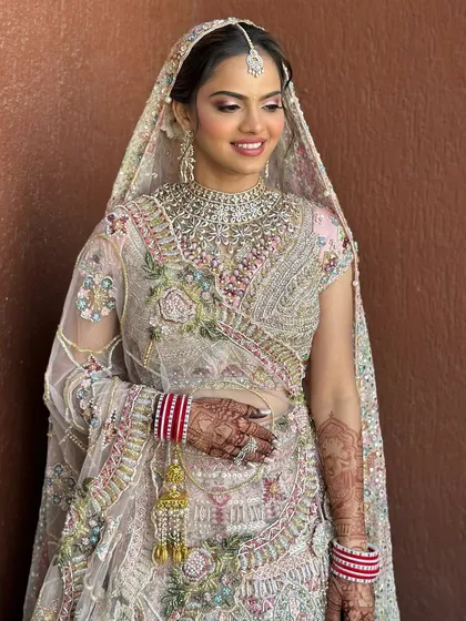 The complete look with the dupatta. The bride looks absolutely radiant in her pastel pink and mint lehenga, with makeup that enhances her features without overpowering her natural beauty.