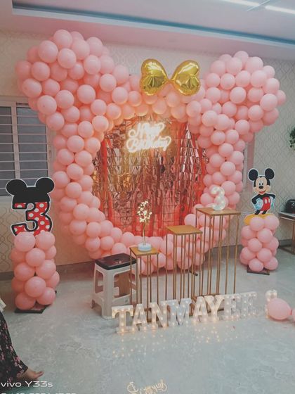 A cute Minnie Mouse theme for a third birthday. The centerpiece is a large Minnie head silhouette made entirely of pink balloons, with a golden bow and a shimmer backdrop in the middle.