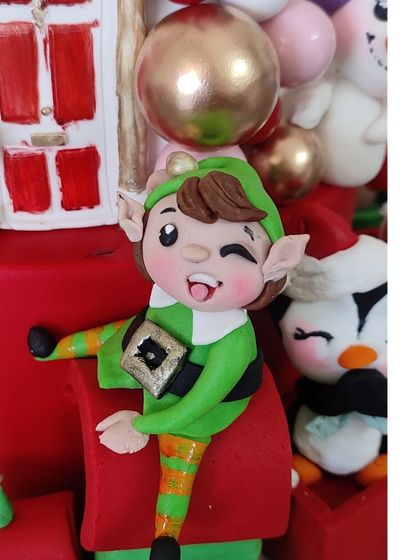 A cheeky little elf winking from the side of the Christmas cake.