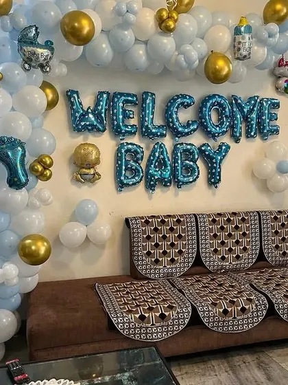 A close-up view of the "Welcome Baby" foil balloons and the surrounding organic garland.
