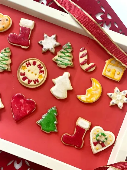 A close-up of our hand-decorated Christmas sugar cookies. Each cookie is a unique piece of edible art, with shapes like Christmas trees, stockings, hearts, and stars, all decorated with colourful royal icing.