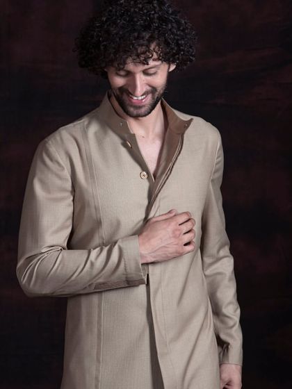 A sherwani-cut kurta in a neutral beige tone. The contrasting inner collar adds a subtle detail to this minimalist and sophisticated garment, perfect for a man with a refined taste.