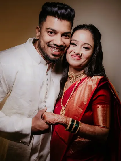 A warm and happy portrait of a couple during their engagement shoot. Her radiant smile and traditional red saree complement his simple white kurta, capturing the pure joy of starting their new life together.