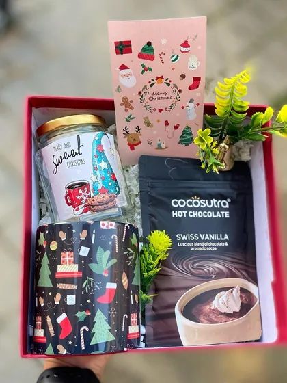 Get cozy for the holidays with our signature Christmas hamper. This set includes a festive mug, a jar of sweet treats, and premium Swiss vanilla hot chocolate mix, all beautifully arranged in a red gift box. It's the perfect warm and thoughtful gift for friends, family, or colleagues.