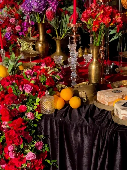 More details from the extravagant tablescape, where cascades of red flowers spill onto the floor. The design was intended to feel abundant and overflowing with life.