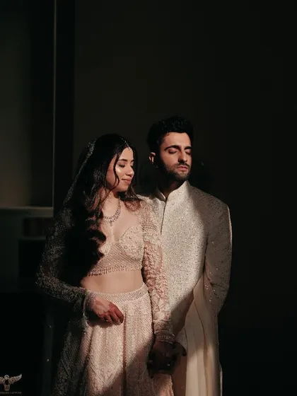 A high-contrast, artistic portrait. The couple is captured in a sliver of light, creating a dramatic and moody image that emphasizes their silhouettes and close bond.