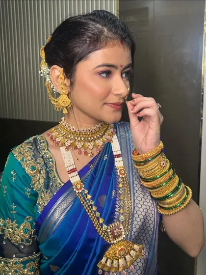 A side profile showing the intricate jewelry and the flawless makeup. The look is a perfect blend of tradition and modern artistry.