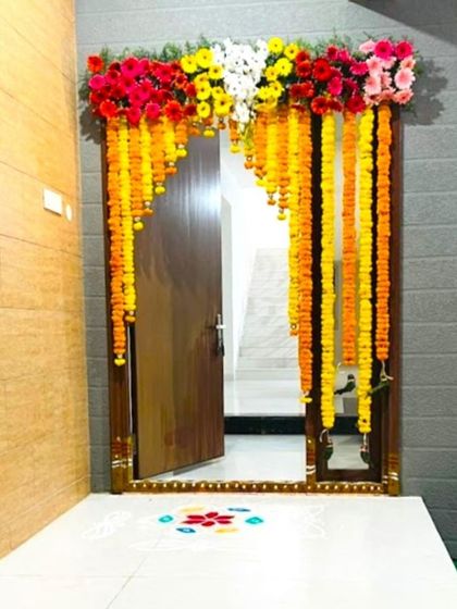 A Gruhapravesam decoration in Bangalore. The entrance is decorated with marigold garlands and a colorful rangoli on the floor.
