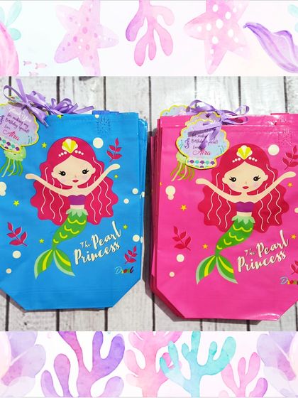 The vibrant mermaid-themed gift bags come in pink and blue, featuring "The Pearl Princess" design. They are the perfect way to present the gift.