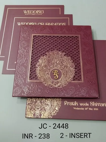 A rich maroon invitation with a laser-cut lattice window and a gold monogram. The design is intricate and luxurious, ideal for a formal wedding.