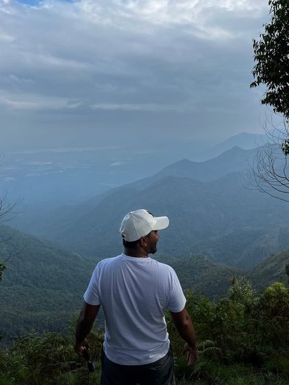 A trekker looks out over the rolling hills and valleys from a viewpoint in Kodaikanal.