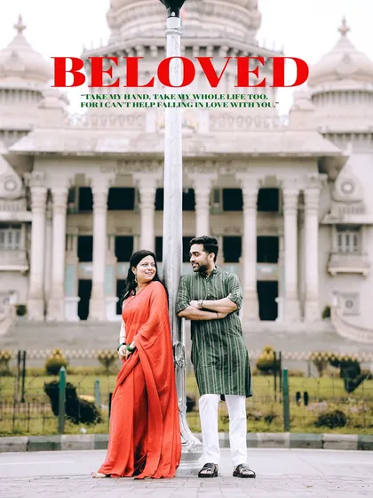 An iconic pre-wedding photograph featuring a couple in traditional Indian outfits posing in front of the grand Vidhana Soudha in Bangalore, blending romance with architectural beauty.