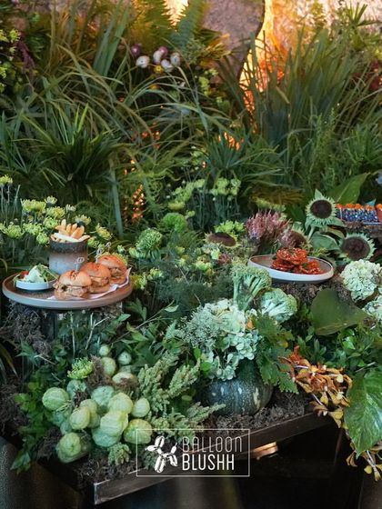 A food display nestled within a bed of lush greenery and flowers, creating an integrated and natural feel.