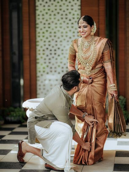 A playful moment as the groom helps the bride with her saree, a gesture of care and partnership.
