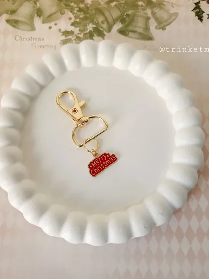 A 'Merry Christmas' word charm keychain, perfect for spreading holiday cheer. The bright red enamel makes it stand out.