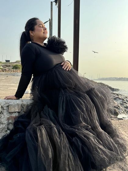 This black tiered gown combines comfort and style with its full-sleeved top and voluminous net skirt. It's a versatile piece that works for both studio and outdoor shoots.