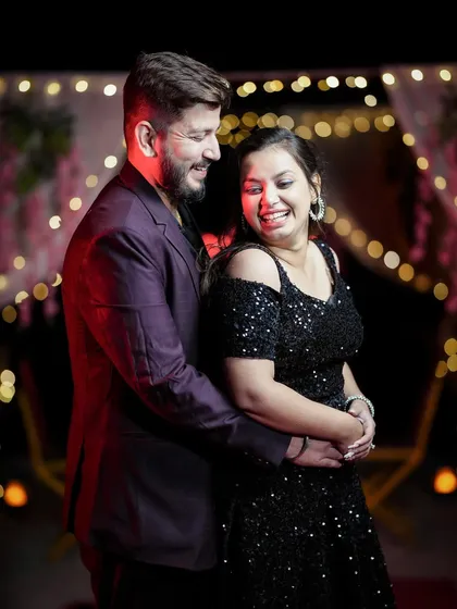 A happy, candid moment from a pre-wedding shoot with a bokeh background of festive lights.