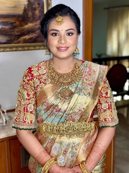 A radiant mother-to-be at her baby shower, glowing in a floral silk saree and antique gold jewellery.