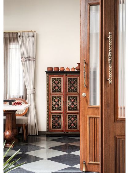 A peek into the dining room, where the checkered floor, custom teak furniture, and hand-painted vintage cabinet create a rich tapestry of Indian heritage.