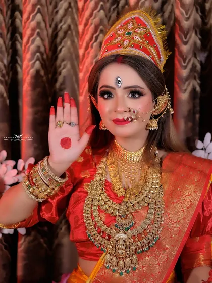 The model poses with her hand raised in a blessing gesture (abhaya mudra), embodying the goddess.