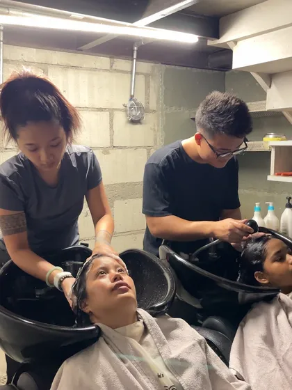 The hair wash is a fundamental skill. Our students are learning proper washing and conditioning techniques at the backwash station, an essential part of any salon service.