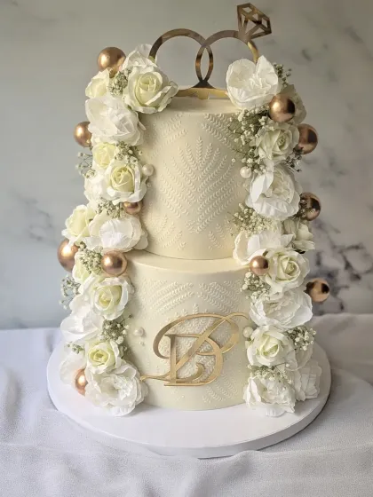 It was an honor to create this engagement cake for a loyal client. This two-tier design is adorned with columns of fresh white flowers and baby's breath, accented with gold spheres and a custom initial topper.