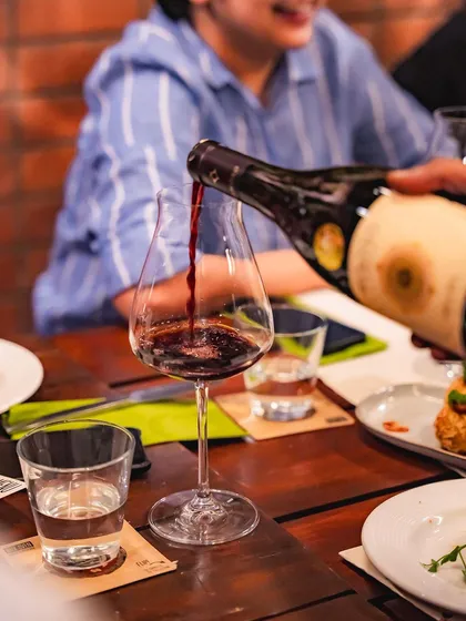 Pouring a glass of red wine at our Wine and Pizza Night, a perfect pairing for our wood-fired dishes.