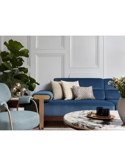 A detail shot of the living room, focusing on the soothing blue sofa and custom lounge chair against the classical wall moulding.