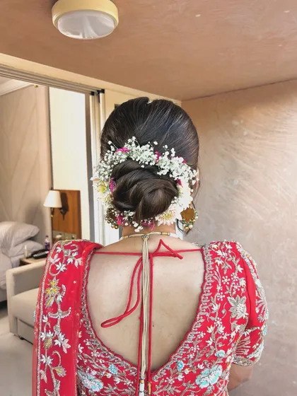 A classic low bun wrapped in a garland of baby's breath and other small flowers. This is a timeless and romantic choice for any bride or bridesmaid.
