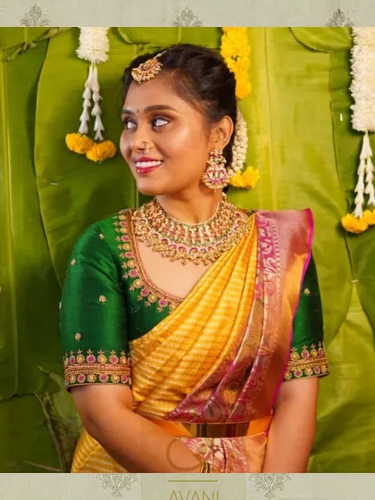 A bride in a yellow and green Kanchipuram saree. Her custom green blouse features delicate embroidery along the neckline and sleeves.